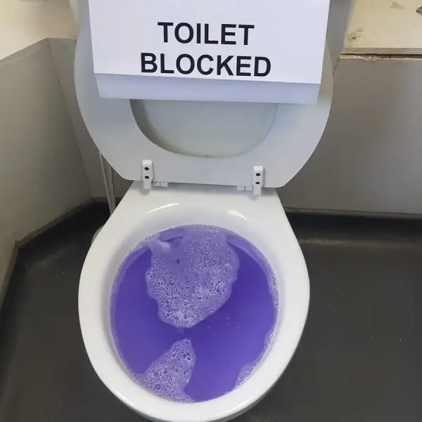 Blocked toilet with a "toilet blocked" sign, ready to be cleared