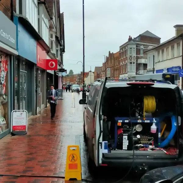 Van with the jetting hose reel open on a high street, clearing blocked drains