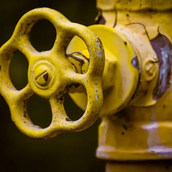 Close-up view of a rusty yellow shut-off valve, emphasizing industrial wear.