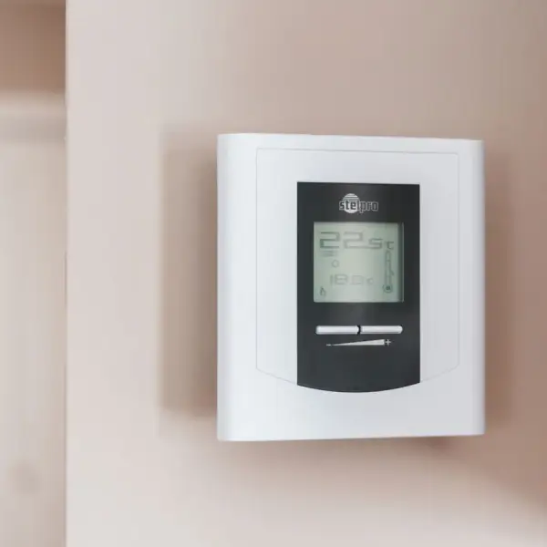 Close-up of a modern digital thermostat mounted on a wall, displaying temperature settings in Celsius.
